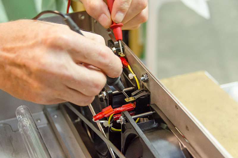 An engineer tests the electrical connections on an enclosure.